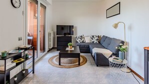 Un salon moderne avec un canapé, une table basse, un téléviseur et une bibliothèque.