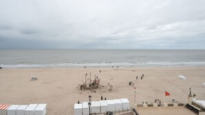 A beach with a lifeguard tower, a lifebuoy, and a flag. - Lovely apartment for 4 guests with WIFI and TV (De Haan)
