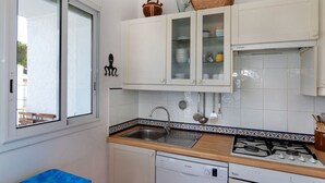 A kitchen with white cabinets, a Bosch dishwasher, a stove, and a window with a view of the outside. - Lovely apartment for 4 guests with TV and terrace (Llançà)