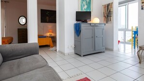 A modern living room with a grey sofa, a small table with a lamp, a grey cabinet, and a painting on the wall. - Lovely apartment for 4 guests with TV and terrace (Llançà)