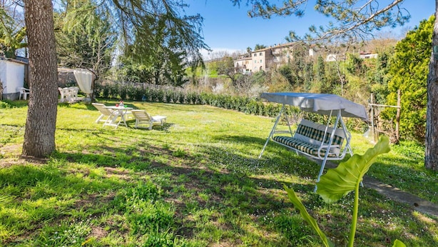 A backyard with a dining table and chairs, a swing, and a large umbrella. - Beautiful private villa for 4 guests with WIFI, patio and pets allowed (Bucine)