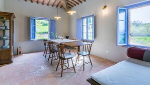A dining area with a wooden table, chairs, and a cabinet. There are windows with blue shutters and a view of greenery outside. - Beautiful private villa with private pool, WIFI, A/C, TV, patio, pets allowed and panoramic view (Asciano)