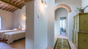 A bedroom with two beds, a hallway with a patterned rug, and a green cabinet. - Beautiful private villa with private pool, WIFI, A/C, TV, patio, pets allowed and panoramic view (Asciano)