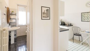 A modern bathroom with a white sink, a toilet, and a shower. There is a towel rack with folded towels and a small potted plant. - Beautiful apartment for 5 guests with A/C, WIFI, TV and balcony (Rome)