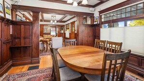 A spacious dining area with a large wooden table and chairs, wooden paneling, and a view through a window. - Enjoy this comfortably furnished, historic Craftsman home just 1 block from downtown McMinnville (McMinnville)