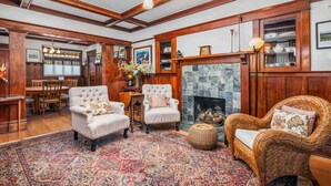 A traditional room with a fireplace, two armchairs, a sofa, and a dining area with wooden furniture. - Enjoy this comfortably furnished, historic Craftsman home just 1 block from downtown McMinnville (McMinnville)