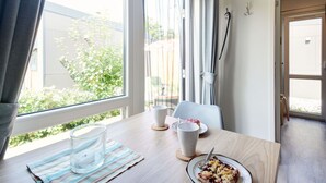 Et værelse med et stort vindue, et bord med mad, et glas vand og en kop.