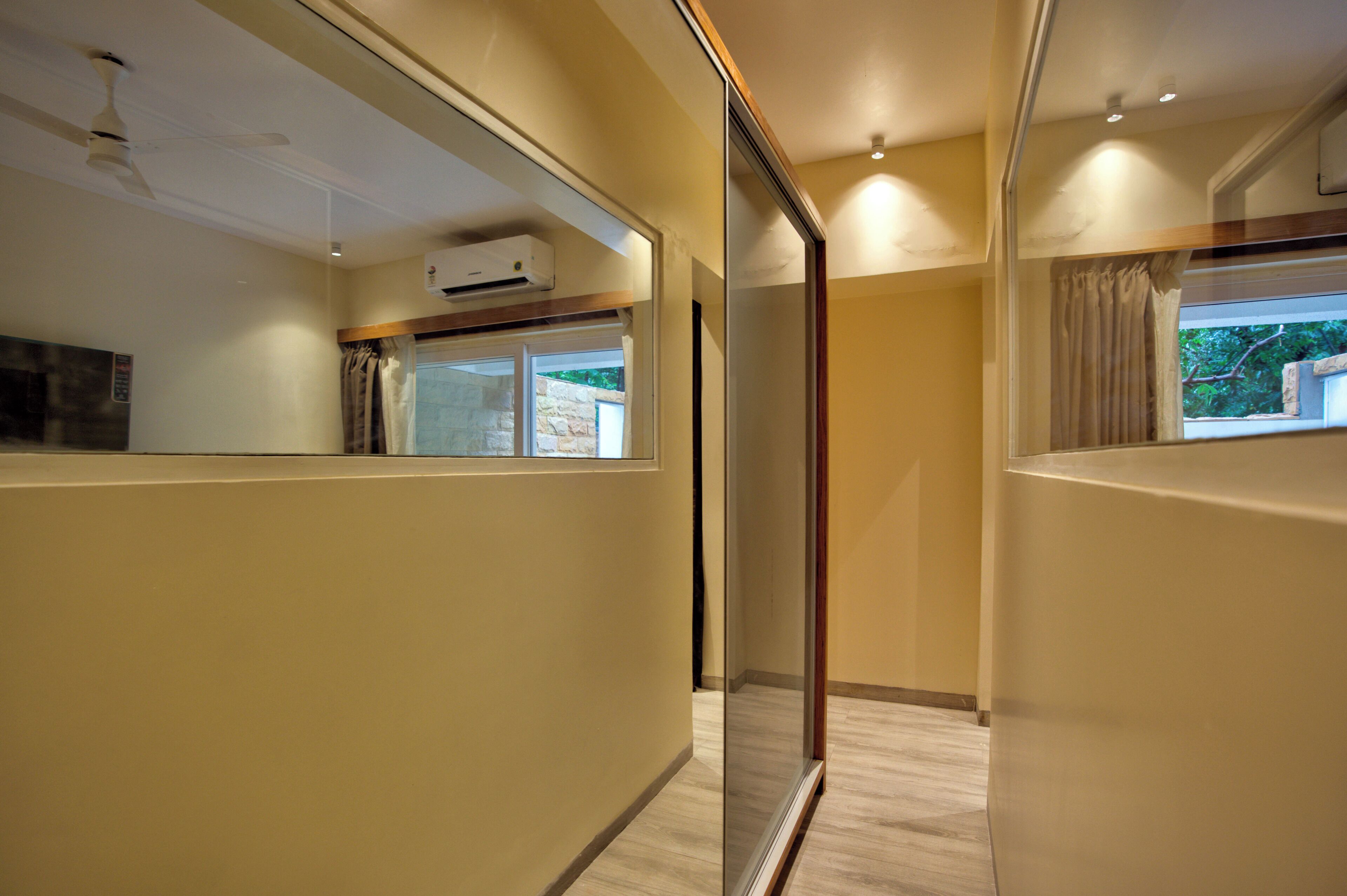 Habitación de hotel moderna con separador de vidrio, ventilador de techo, aire acondicionado y vistas al exterior.