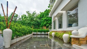 Ein modernes Gebäude mit großen Fenstern, einer teilüberdachten Terrasse und umgebendem Grün.
