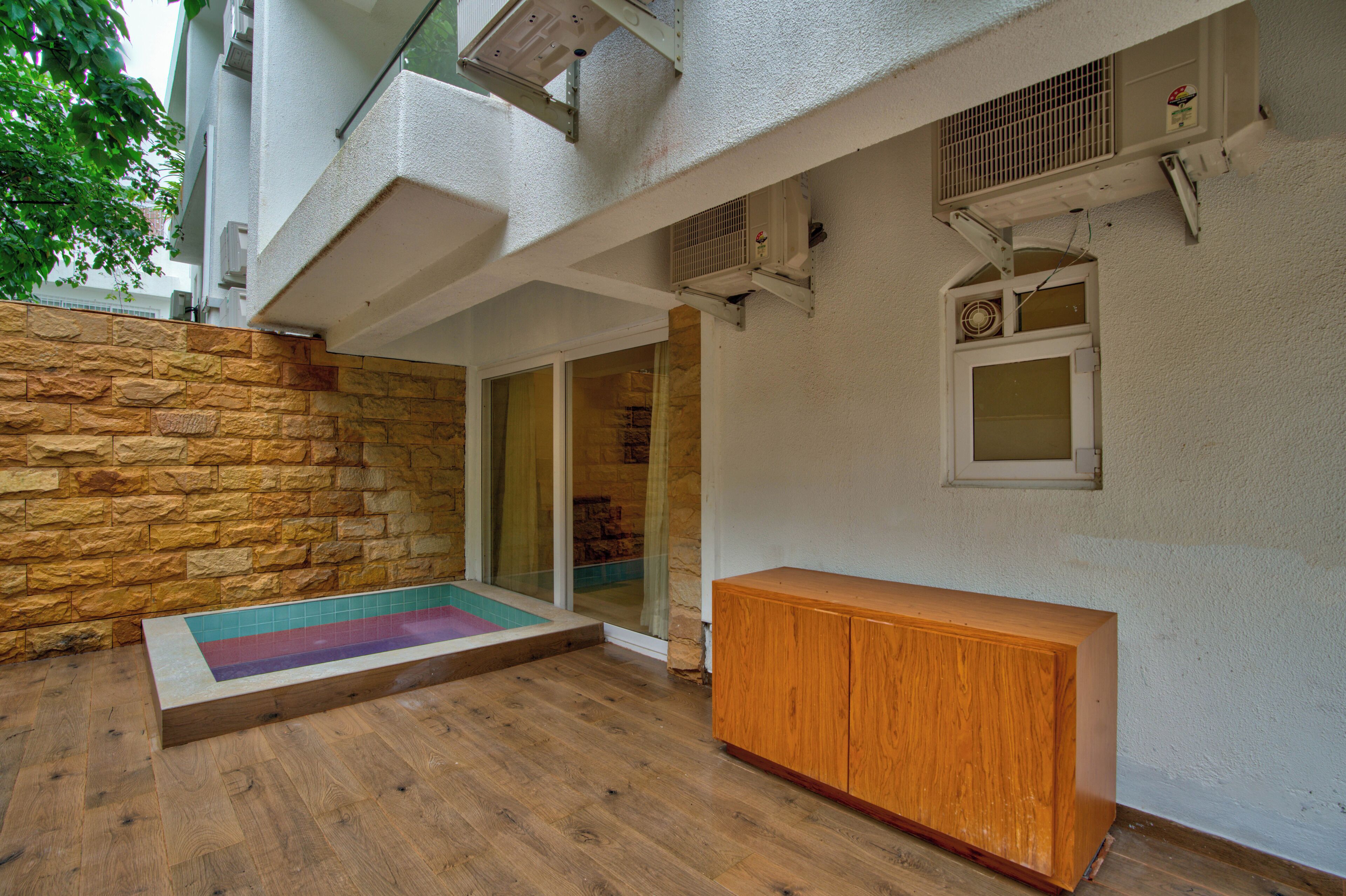 A modern outdoor space with a stone wall, a wooden bench, and a small pool.