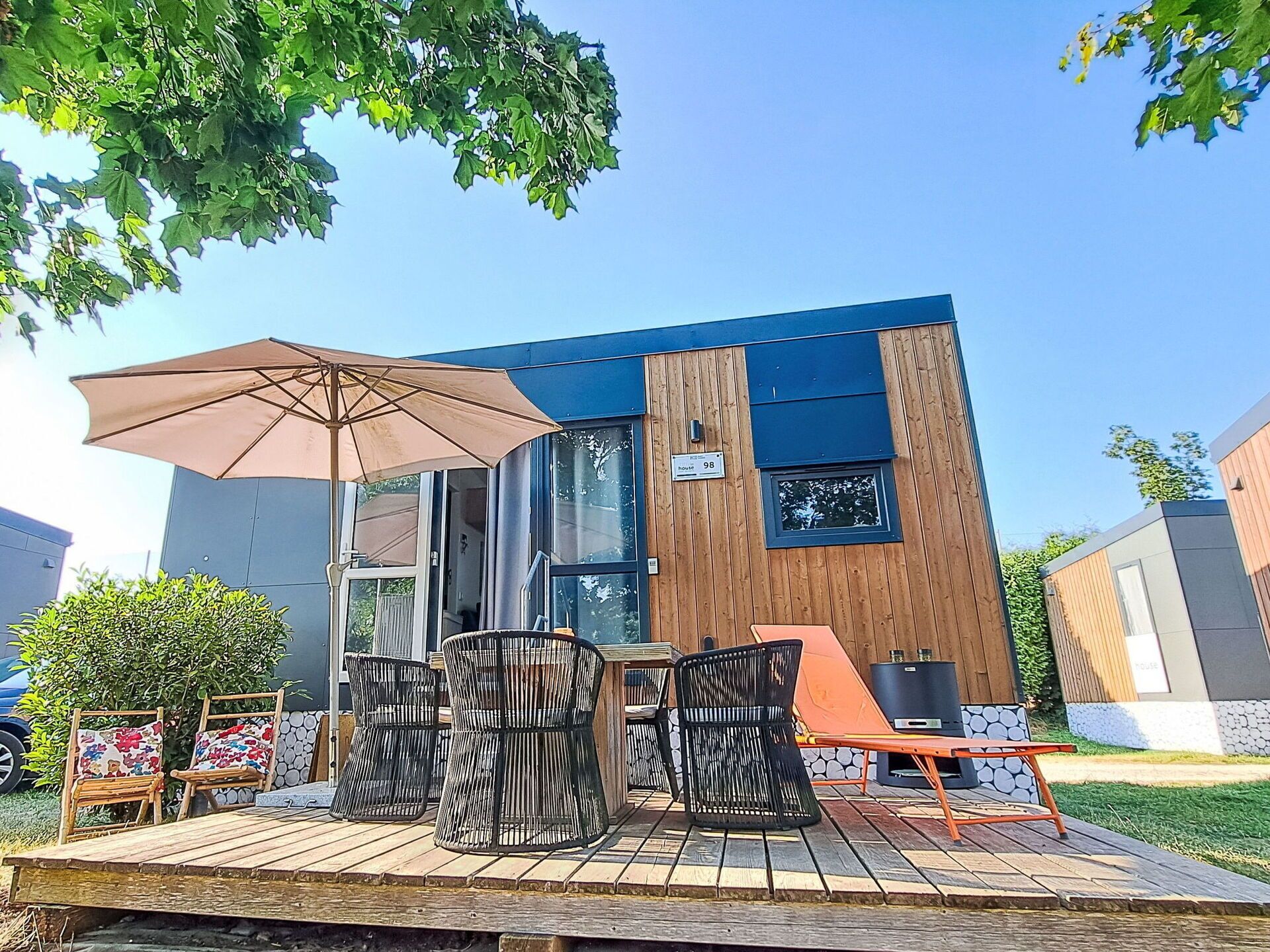 A modern outdoor seating area with a table, chairs, and a large umbrella.