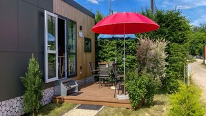 A modern building with a wooden deck, outdoor seating, and a grill area. - Nice apartment in villa for 4 guests with WIFI, TV and terrace (Beilngries)