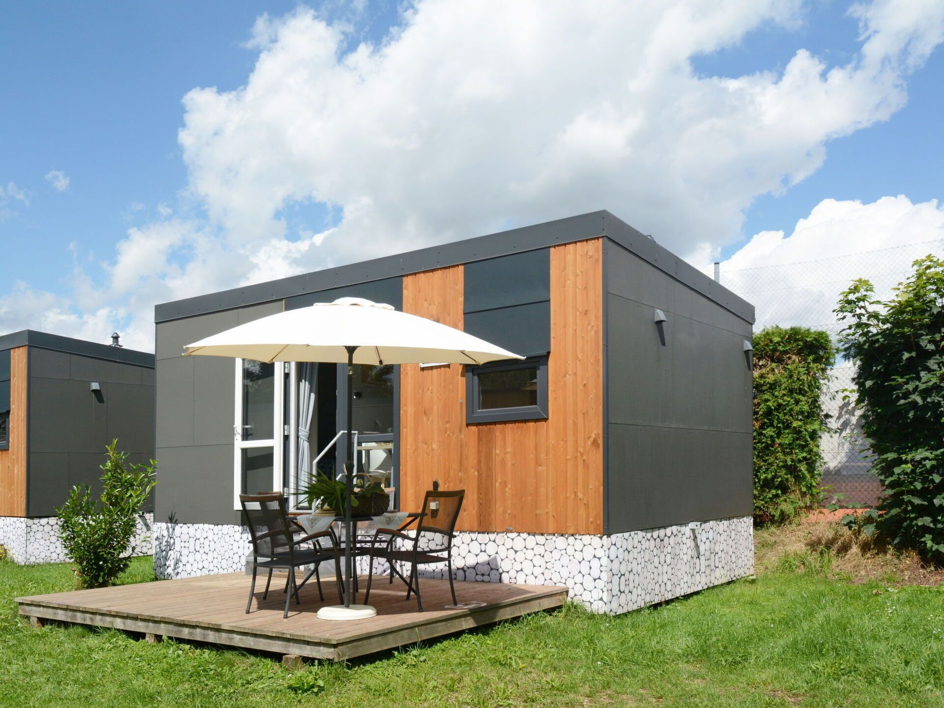 A modern, compact building with a flat roof, large windows, and a wooden accent wall.