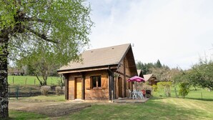 A wooden cabin with a sloped roof, a small porch, and a table with chairs under a pink umbrella. - Beautiful private villa for 5 guests with TV, terrace and pets allowed (Camps-saint-mathurin-léobazel)