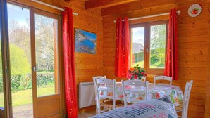 A cozy wooden cabin with a dining area, large windows, and a painting on the wall. - Beautiful private villa for 5 guests with TV, terrace and pets allowed (Camps-saint-mathurin-léobazel)
