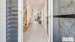 Un interior moderno con una escalera, un pasillo que conduce a un comedor y una pared con textura.