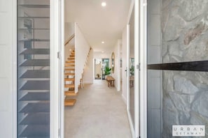 A modern interior with a staircase, a hallway leading to a dining area, and a textured wall.
