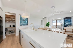 Une cuisine moderne dotée d’un îlot central, de meubles blancs et d’un ventilateur de plafond.