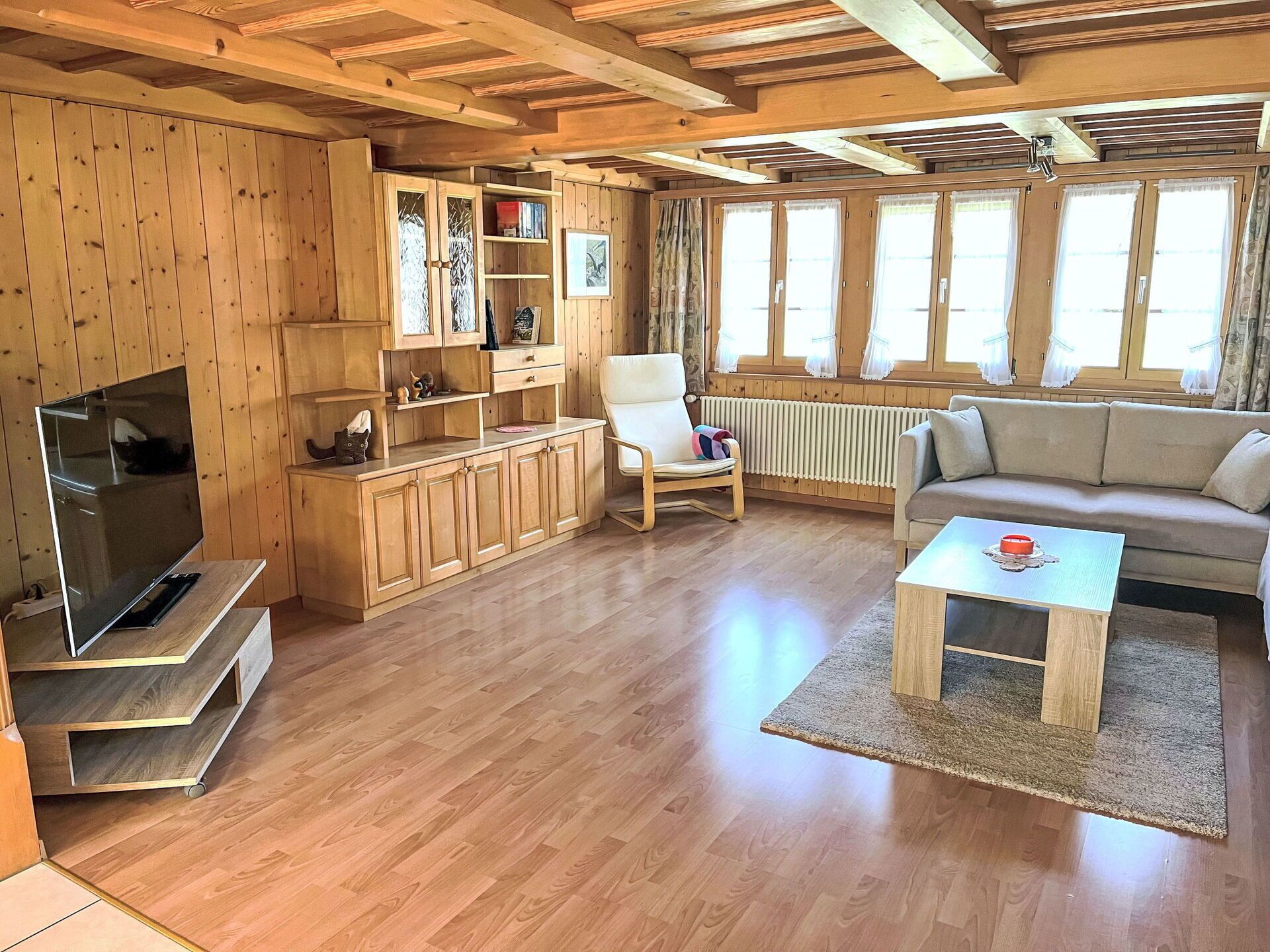 Ein gemütliches Wohnzimmer mit Holzböden, einer Couch, einem Couchtisch, einem Fernseher und eingebauten Holzböschungen.
