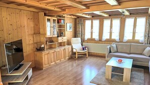 Un salon chaleureux avec un plancher en bois, un canapé, une table basse, un téléviseur et des étagères intégrées en bois.