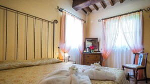 A hotel room with a bed, a dresser, a chair, and a mirror. - Deluxe Double Room (DERUTA)