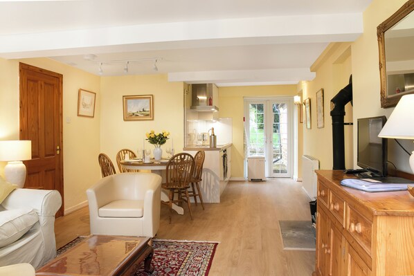 A living room with a sofa, a wooden cabinet, and a dining area with chairs and a table.