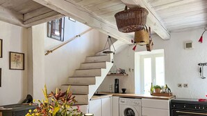 Eine Küche mit Waschmaschine, Backofen und einer Holztreppe.