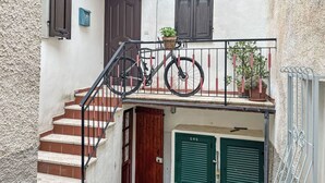 Eine enge Treppe führt zu einer kleinen Veranda, auf deren Geländer ein Fahrrad steht.