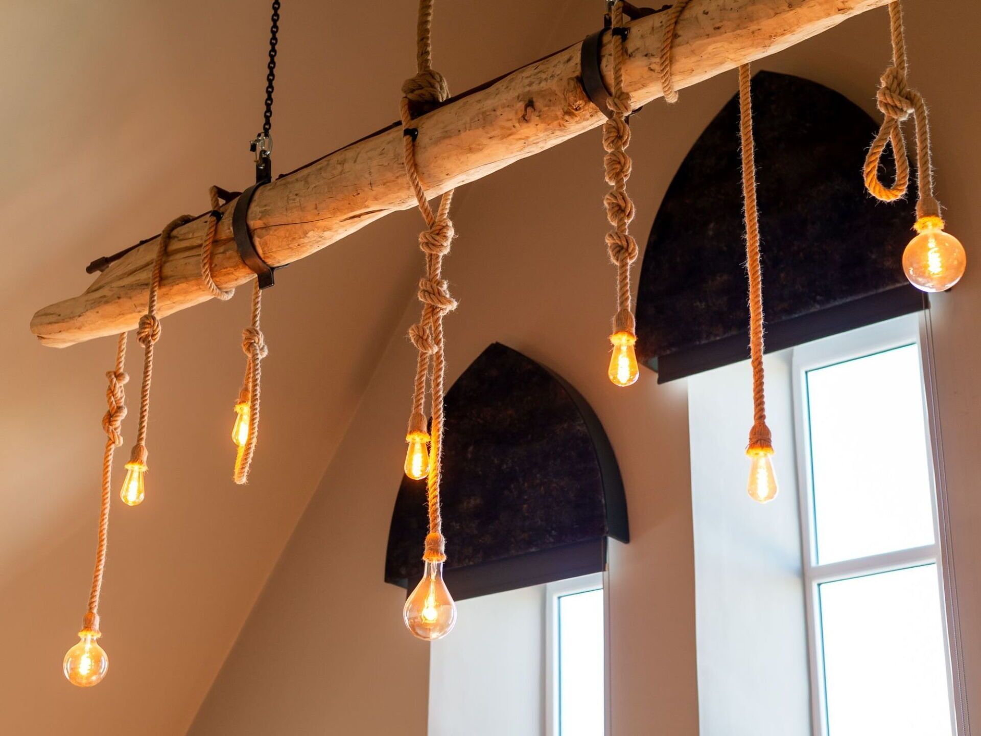 Een rustieke houten balken plafond met zichtbare gloeilampen.