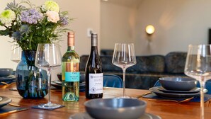 A dining table set with wine glasses, a bottle of wine, and a vase with flowers. - Beautiful private villa for 6 people with WIFI, TV and pets allowed (Newquay)