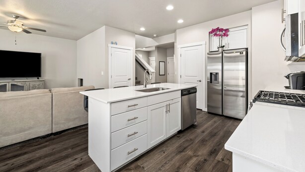 A modern kitchen with white cabinetry, stainless steel appliances, and a wooden floor.