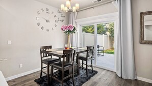 A dining area with a table, chairs, a chandelier, and a view through a glass door to an outdoor space.