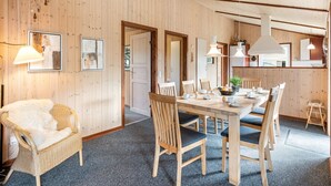 Een kamer met houten lambrisering, een eettafel, stoelen en een rieten stoel.