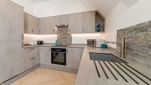 A modern kitchen with built-in appliances, a stone accent wall, and a unique black countertop design.