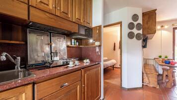 A kitchen with wooden cabinets, stainless steel appliances, a granite countertop, and a dining area with a bench and table.