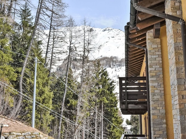A narrow street flanked by trees and a mountain in the background.