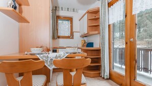 Un coin repas chaleureux avec une table en bois, des chaises et une fenêtre donnant sur un paysage enneigé.