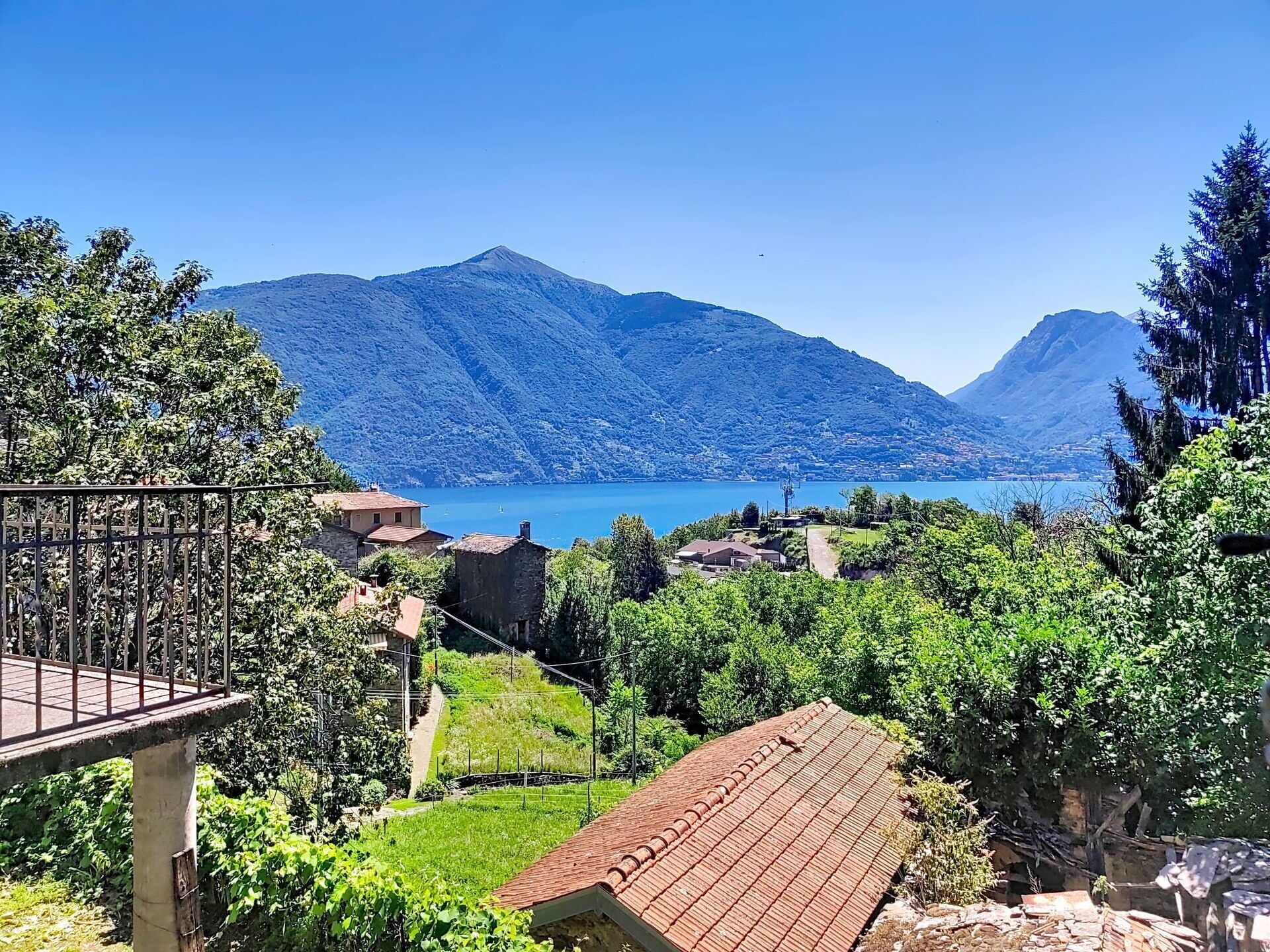 A mountainous landscape with a lake, houses, and a wooden deck.