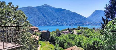 A mountainous landscape with a lake, houses, and a wooden deck.
