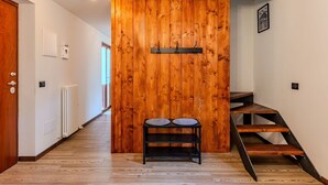 Un pasillo con un separador de madera, un banco de metal negro y una escalera.