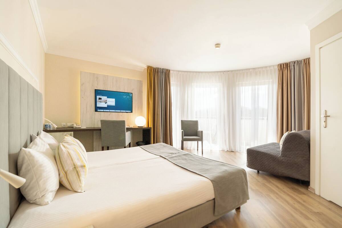 Une chambre d’hôtel avec un lit, un bureau, une chaise et un téléviseur.