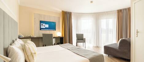 A hotel room with a bed, a desk, a chair, and a television.