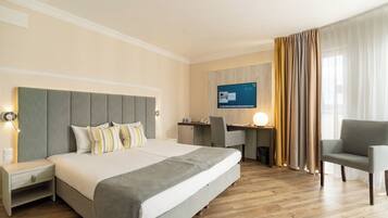 Una habitación de hotel con una cama grande, un escritorio, una silla y un televisor en la pared.