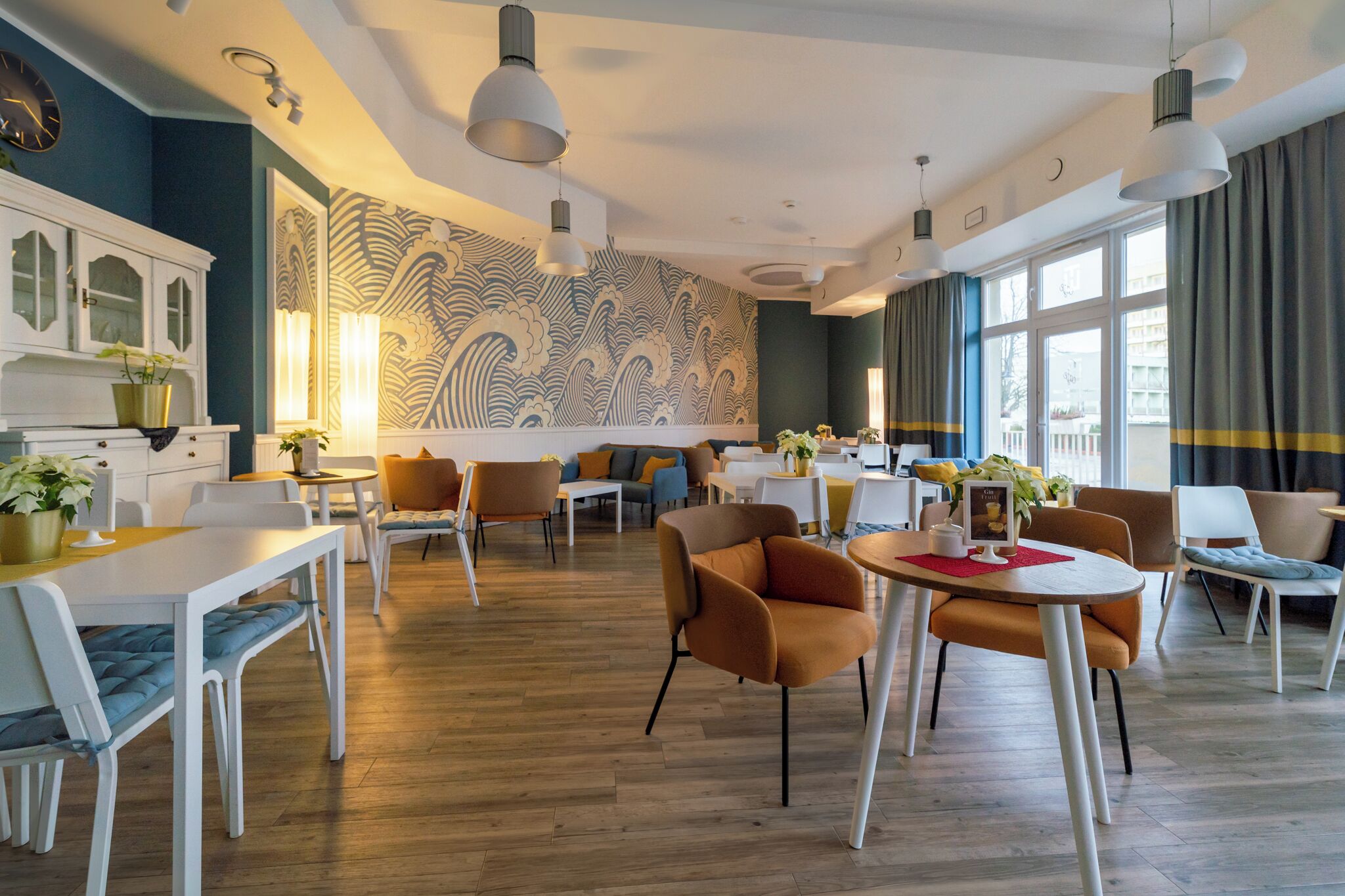 A modern hotel lobby with a wooden floor, white furniture, and a large wall mural.