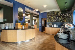 A modern cafe with wooden counters, a mirror, and a wall with a leafy pattern. - Hotel & Spa Trzy Wyspy (Swinoujscie)