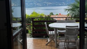 Un balcon avec une table et des chaises, donnant sur un lac et des montagnes.