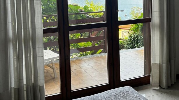 Une chambre avec une grande fenêtre donnant sur un paysage magnifique, avec un lac et des montagnes en toile de fond.