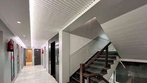 A modern interior with a staircase, a hallway, and a door leading to a room. - Hotel Rockland Residency (Dehradun)