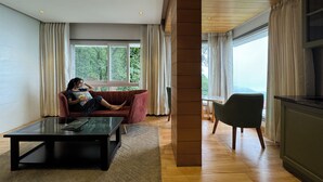 A modern living room with a sofa, a coffee table, and a dining area. - Hotel Rockland Residency (Dehradun)