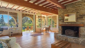 A spacious living area with wooden beams, a stone fireplace, and a view of the outdoors. - Wonderful private villa for 6 people with WIFI, A/C, TV, terrace, pets allowed and panoramic view (Le Lavandou)